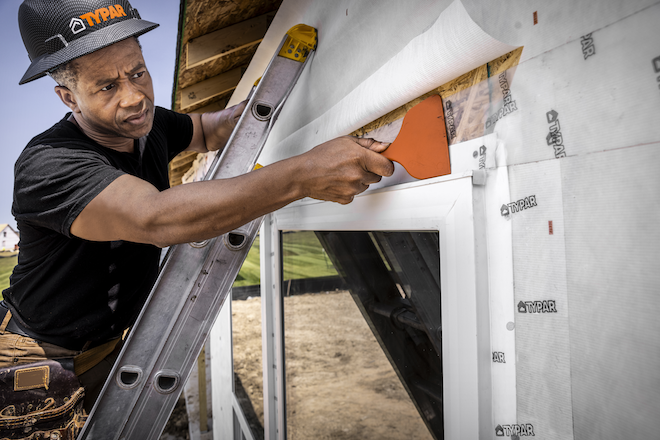 Man installing window flashing with housewrap