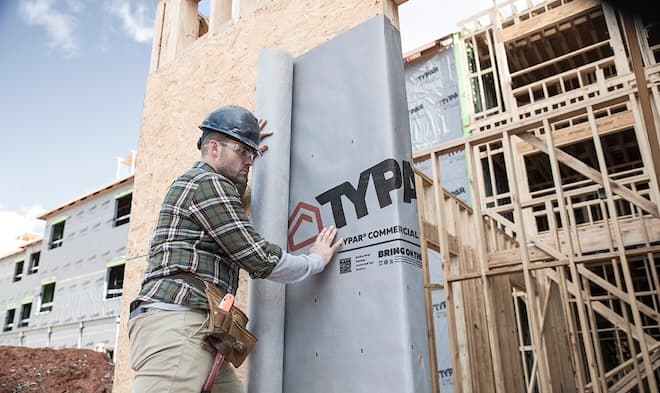 Construction worker installs commercial building wrap