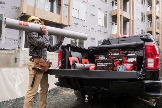 Worker carriers TYPAR Commercial from truck to jobsite